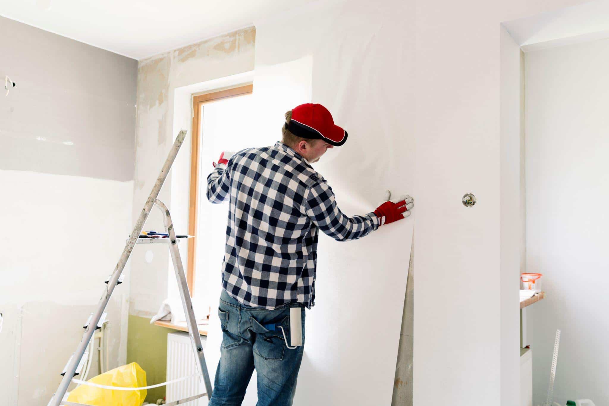 young-man-worker-is-putting-up-wallpapers-on-the-wall